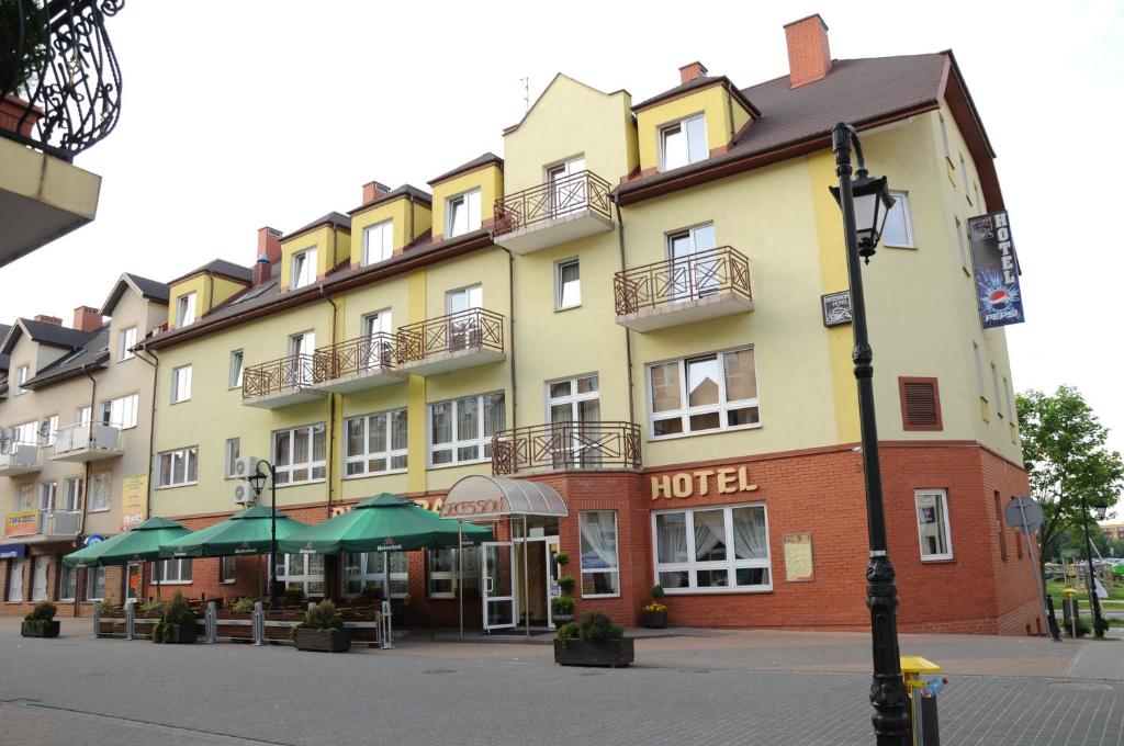 a hotel on a street with umbrellas in front of it at Secession Hotel in Łęczna