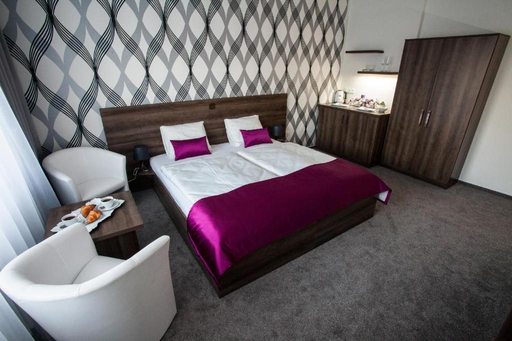 Un dormitorio con una cama con sábanas moradas y una silla en Penzion Olomouc, en Olomouc