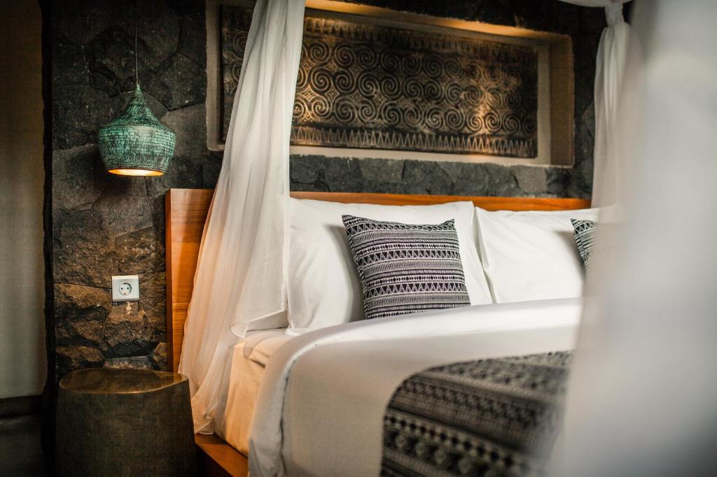 a bedroom with a bed with white sheets and pillows at Ubud Season Villas in Ubud