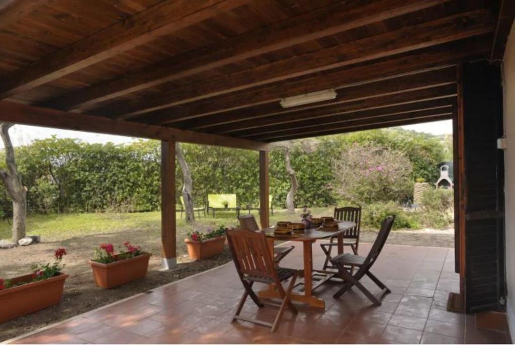 une terrasse avec une table et des chaises sous une pergola en bois dans l'établissement Villa il Caminetto, à Marongiu
