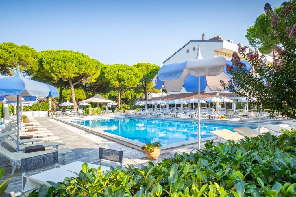 a swimming pool with chairs and umbrellas at Hotel Al Cigno in Lignano Sabbiadoro