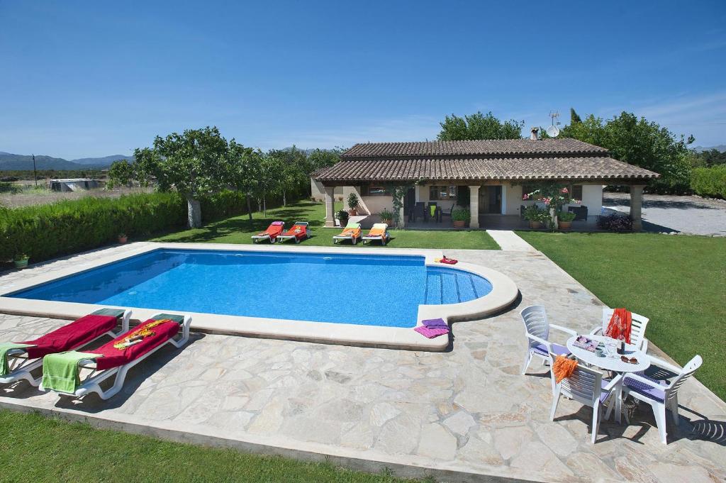 a swimming pool with chairs and a table and a house at Villa BURGUES in Alcudia