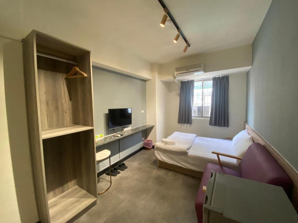 a small hotel room with a bed and a desk at Fengjia Gift Box Homestay in Taichung