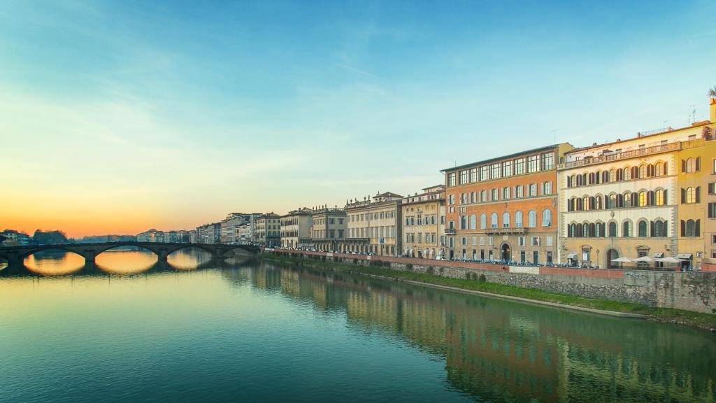 vistas a un río con edificios y un puente en Hotel Bretagna Heritage - Alfieri Collezione, en Florencia