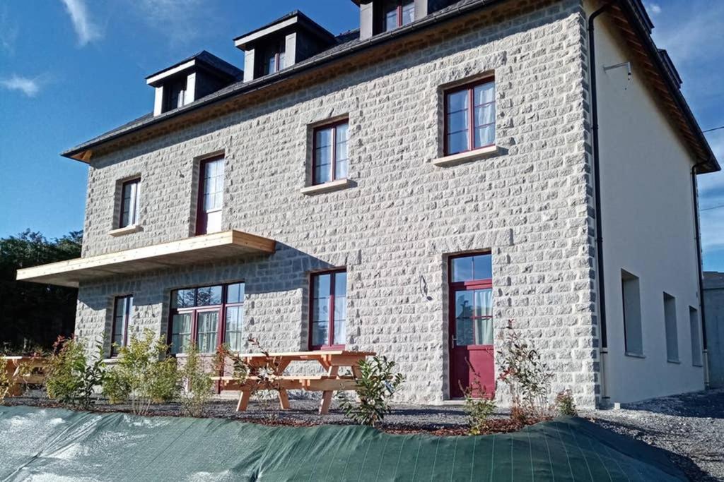 una casa de ladrillo blanco con puerta roja en Gîte de Granit Bleu en Besse-et-Saint-Anastaise