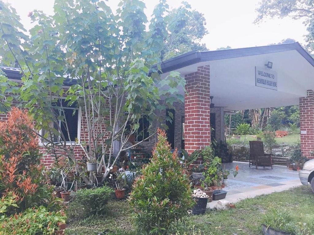 a brick house with a pavilion with trees and plants at Keenomulok Holiday Home in Ranau