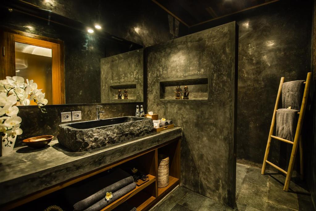 a bathroom with a stone sink and a mirror at Ubud Season Villas in Ubud