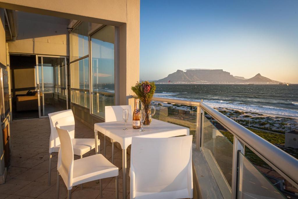 una mesa y sillas en un balcón con vistas al océano en Spacious Luxury 3 Bedroom Apartment B401 Sea Spray, en Ciudad del Cabo