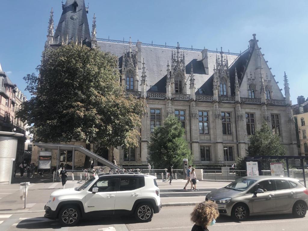 dois carros estacionados em frente a um grande edifício em ROUEN centre ville Palais de Justice em Rouen