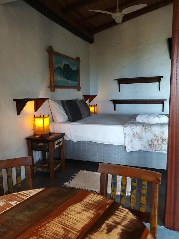 1 dormitorio con 1 cama y 2 mesas y sillas en Pousada Uhuru en Praia do Rosa