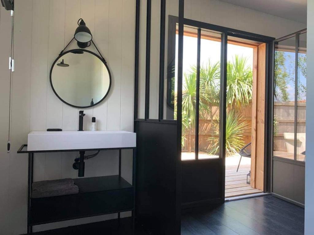 ein Bad mit einem Waschbecken und einem Spiegel neben einer Tür in der Unterkunft La cabane poetique in La Teste-de-Buch
