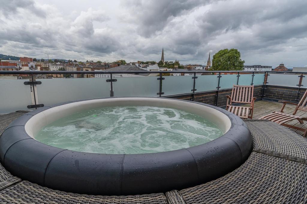 a hot tub on a deck with a view of the water at Central Penthouse with Hot Tub & Views 23 in Cheltenham