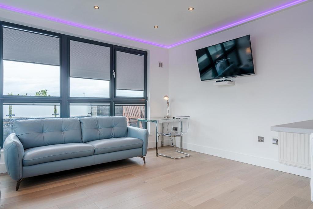 a living room with a blue couch and a tv at Central Penthouse with Hot Tub & Views 23 in Cheltenham