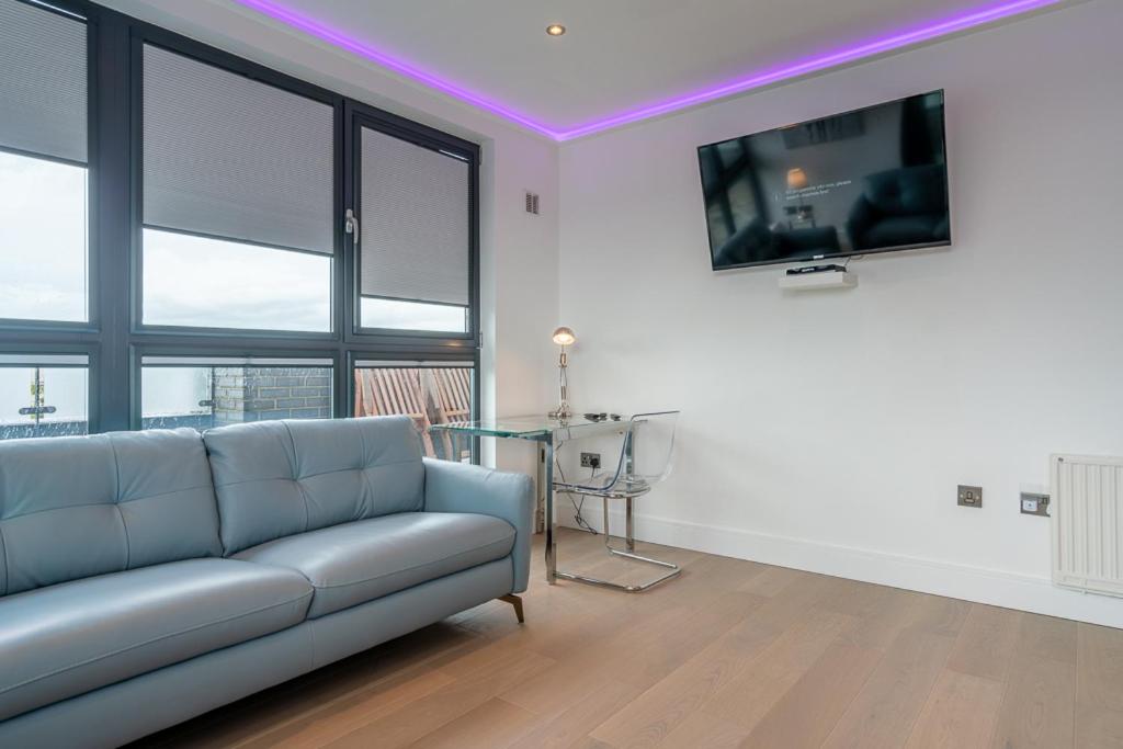 a living room with a couch and a table with a tv at Central Penthouse with Hot Tub & Views 23 in Cheltenham
