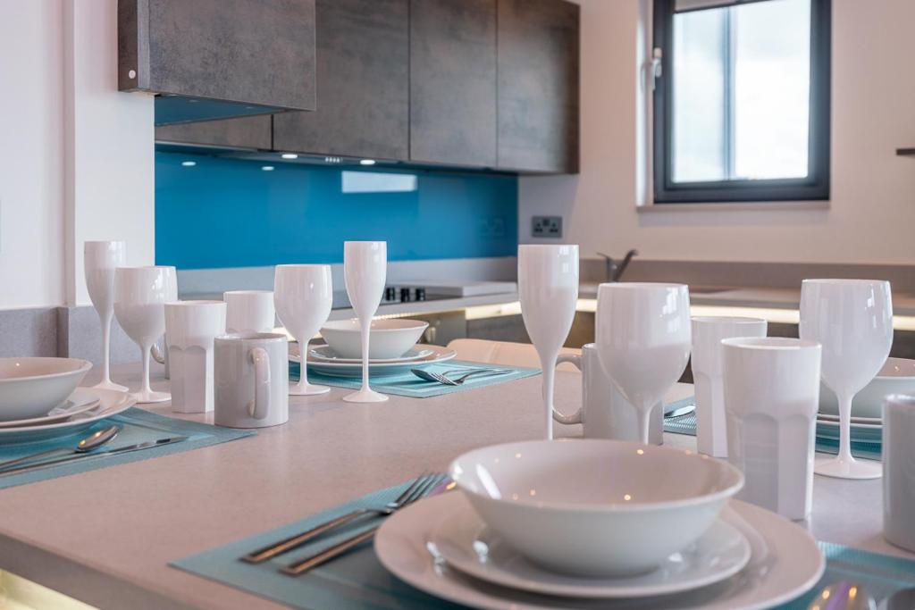 a kitchen with a table with glasses and plates on it at Central Penthouse with Hot Tub & Views 23 in Cheltenham