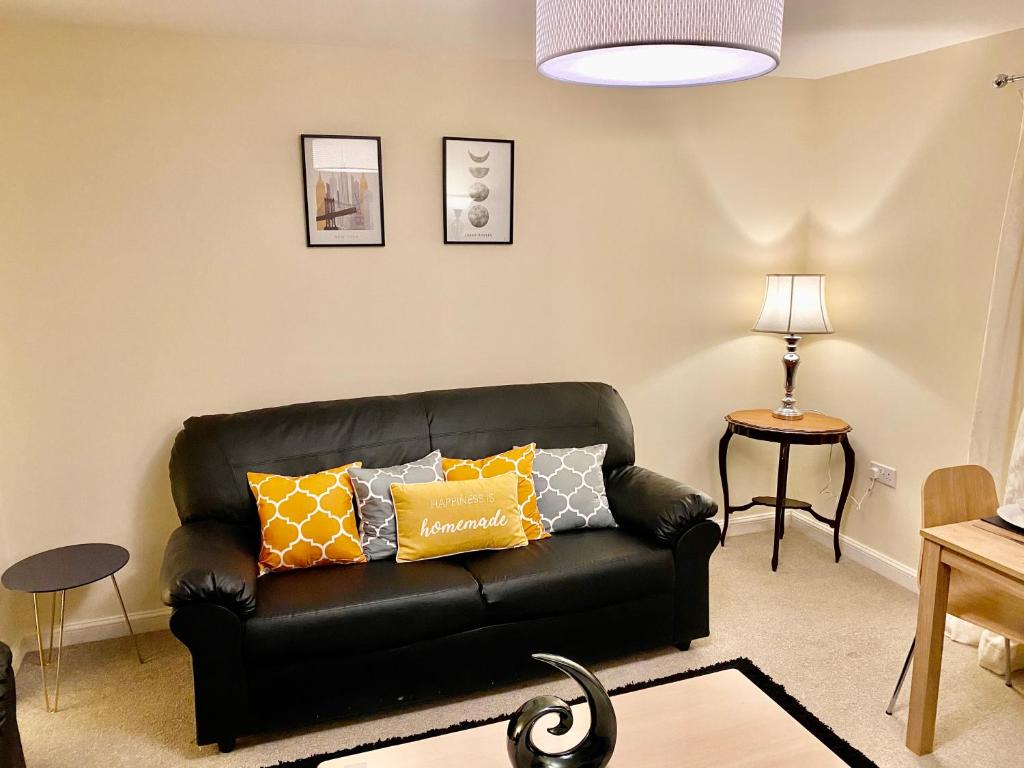 a living room with a black leather couch with yellow pillows at Superior Two-Bed Apartment with Free Parking, CV1 Coventry in Coventry