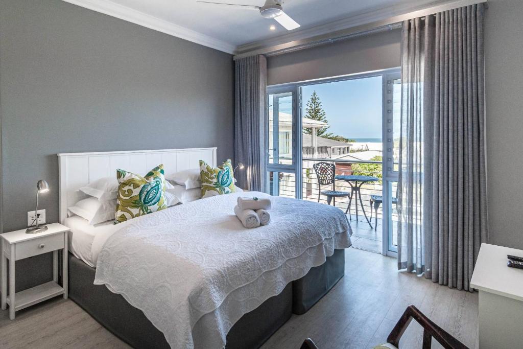 Whale Coast Ocean Villa في هيرمانوس: غرفة نوم مع سرير مع دمية دب عليها