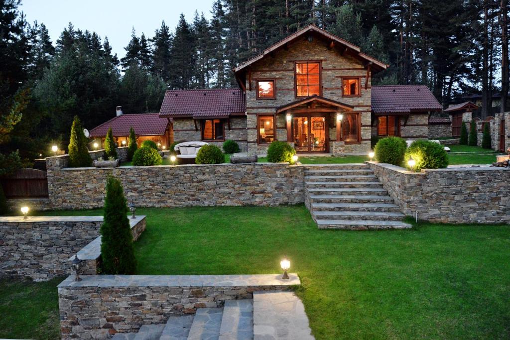 a house with a stone wall and a yard with lights at Moiata Kashta Villa in Popovi Livadi