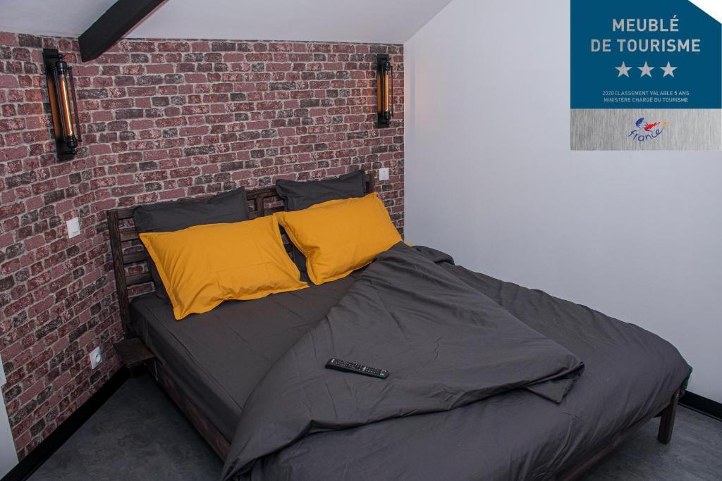 łóżko z 2 poduszkami i ceglaną ścianą w obiekcie Meublé de tourisme 3 étoiles Loft industriel à Fismes w mieście Fismes