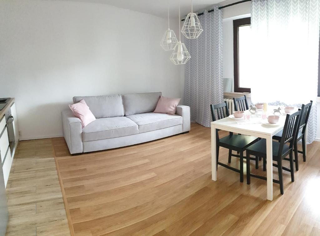 een woonkamer met een bank en een tafel met stoelen bij Corso Nobile Apartament in Płock