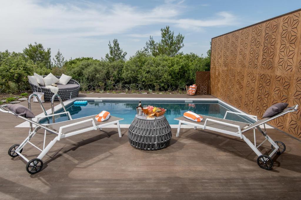 a pool with two chairs and a table next to it at Alonella in Kefar Weradim