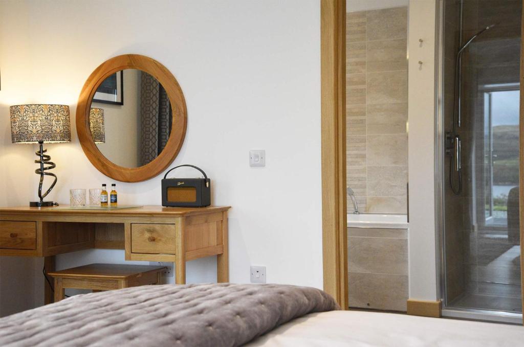 a bedroom with a mirror and a bed and a desk at Woodland Lodge in Port na Long