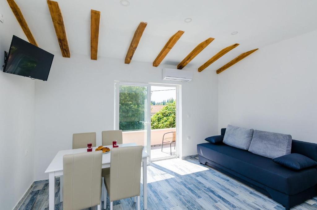 uma sala de estar com uma mesa e um sofá azul em Apartments Dubrovnik Airport em Cilipi