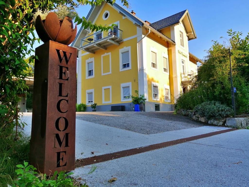 una casa amarilla con un cartel delante en Villa Komposch - adults only, en Reifnitz