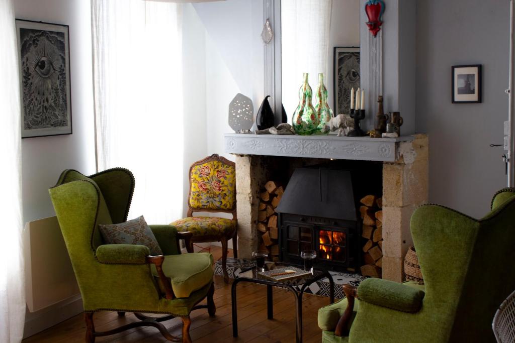 een woonkamer met groene stoelen en een open haard bij MAISON MATEJEWSKI chambre d'hôtes avec jardin in Blaye