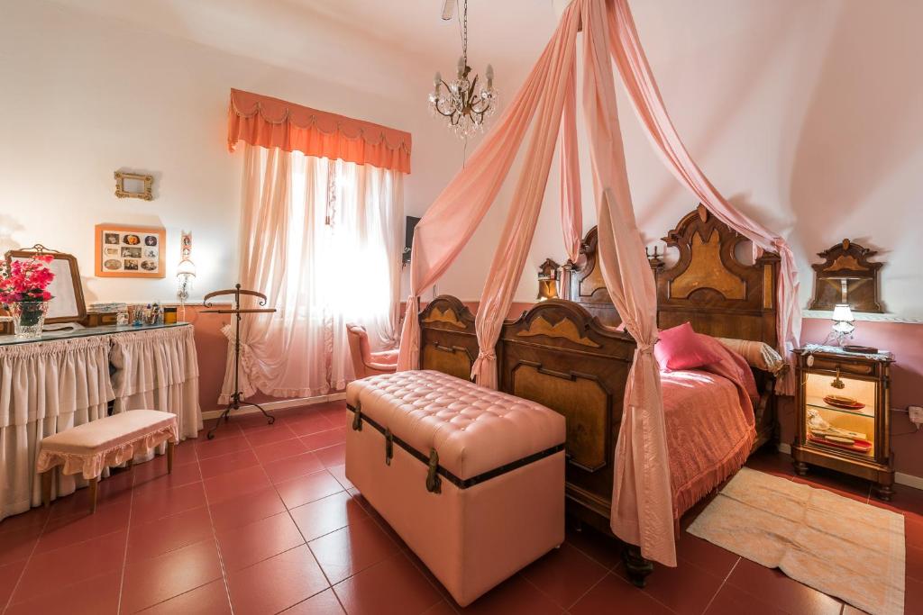 1 dormitorio con cama con dosel y reposapiés en Villa Mariella Pittorino - camere in B&B, en Leni