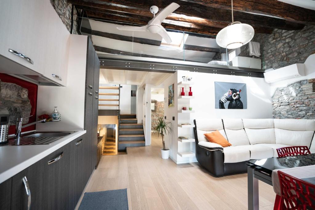 cocina y sala de estar con sofá y escalera en LOFT in PIAZZA con soppalco en Cividale del Friuli