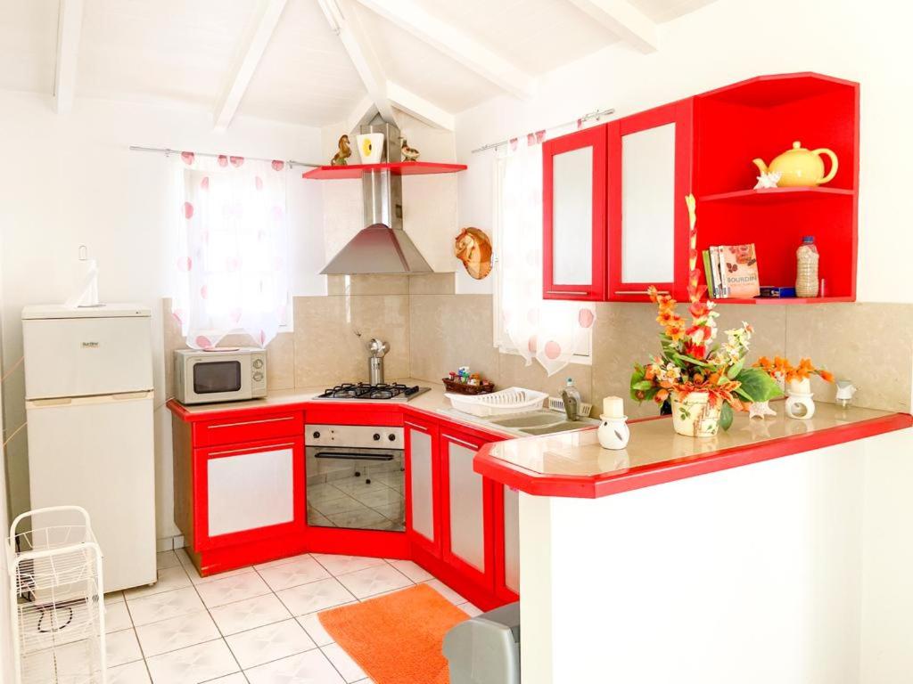 cocina roja con nevera blanca y armarios rojos en Villa Marine, en Sainte-Anne