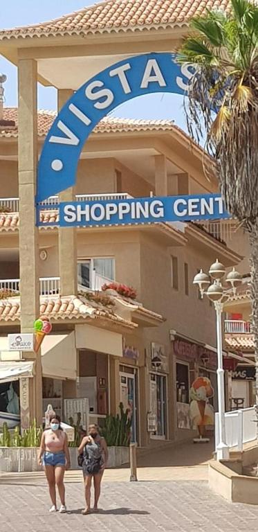 two people walking in front of a shopping center at PLAYA LAS VISTAS LOFT in Los Cristianos