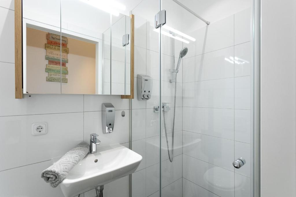 biała łazienka z umywalką i prysznicem w obiekcie Apartment, modern und neu renoviert w Wiedniu