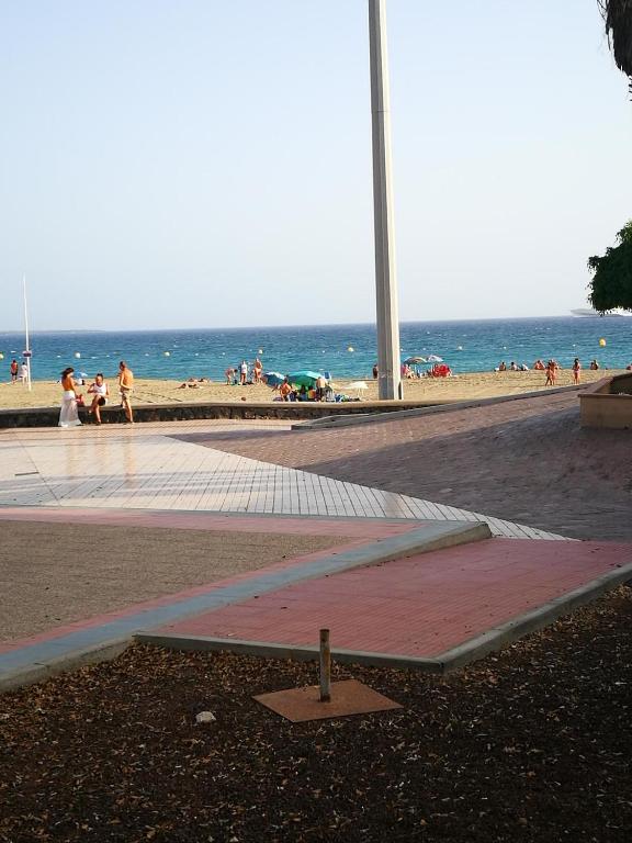 a sandy beach with people walking on the beach at PLAYA LAS VISTAS LOFT in Los Cristianos