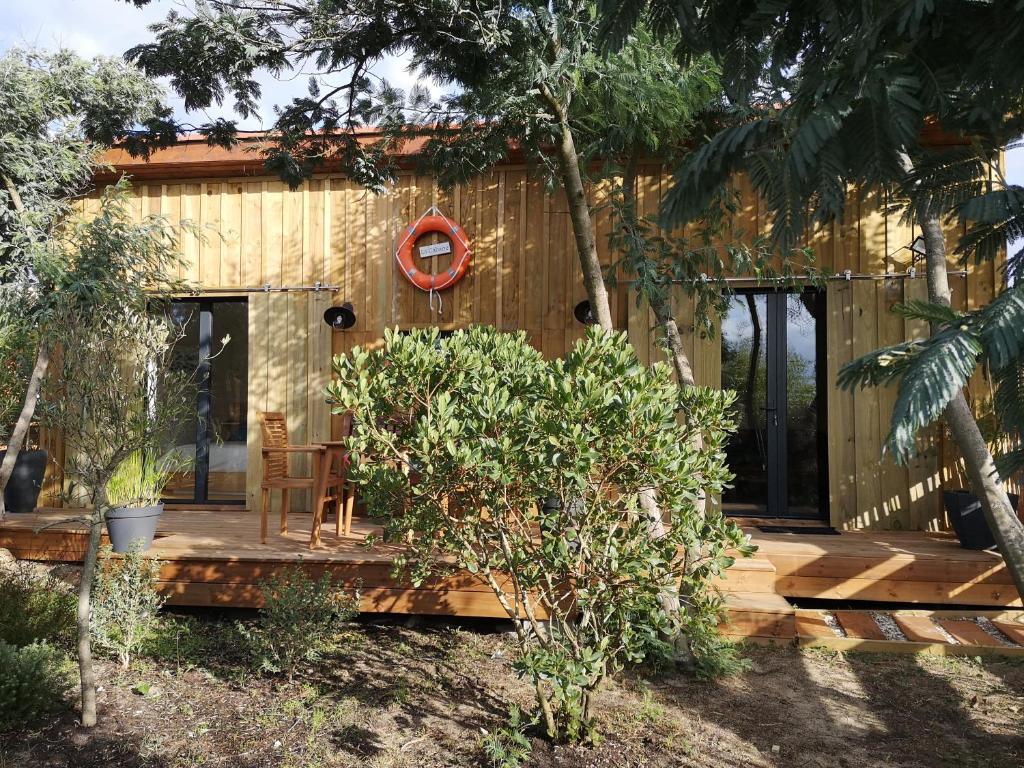 a wooden cabin with a deck in a yard at la cabane vensac ocean montalivet in Vensac