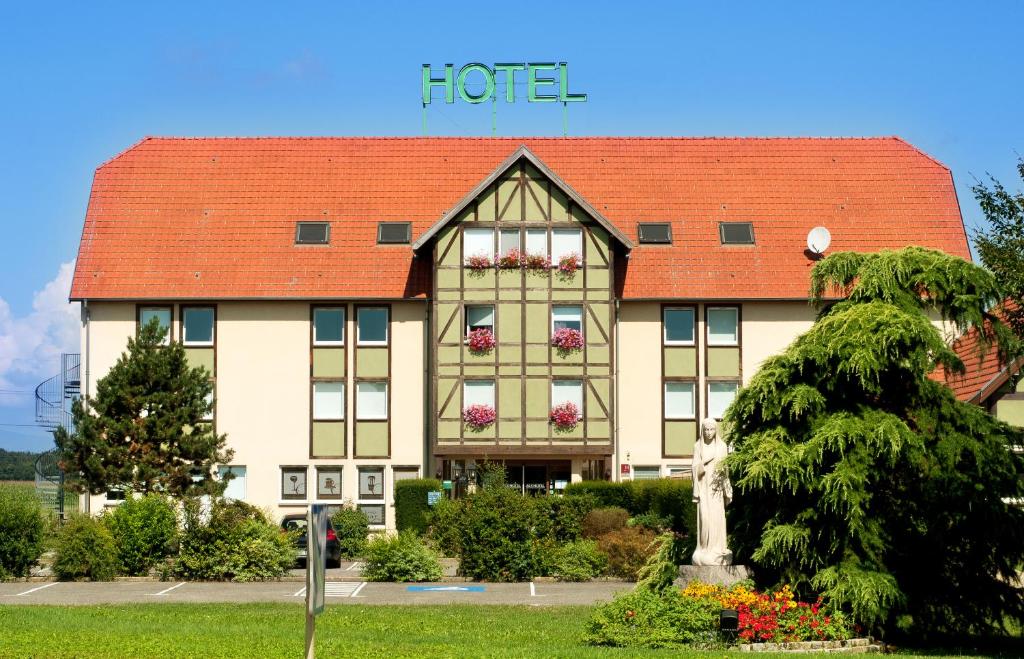 un grand bâtiment avec un toit rouge dans l'établissement Als Hôtel, à Ottmarsheim