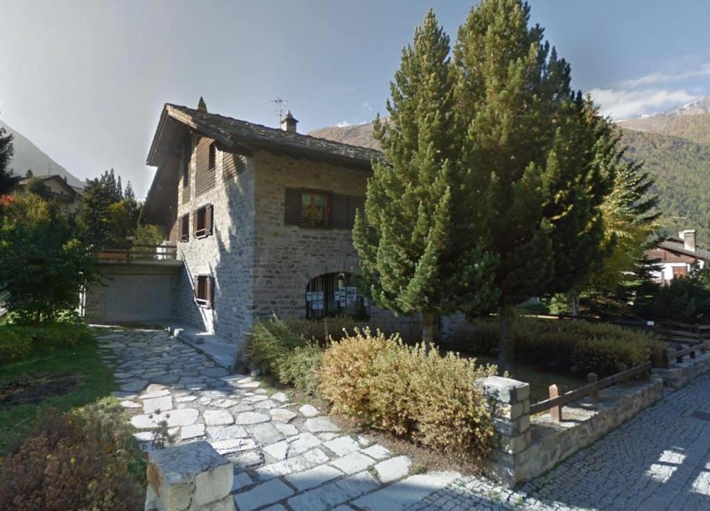une maison en pierre avec un arbre et une allée en pierre dans l'établissement Il Pino Cembro, à Cogne