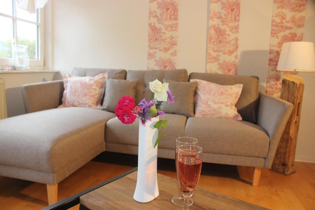 a living room with a couch and a vase with flowers on a table at Ferienidyll Aumühle, "Wiesengrund" in Rot am See