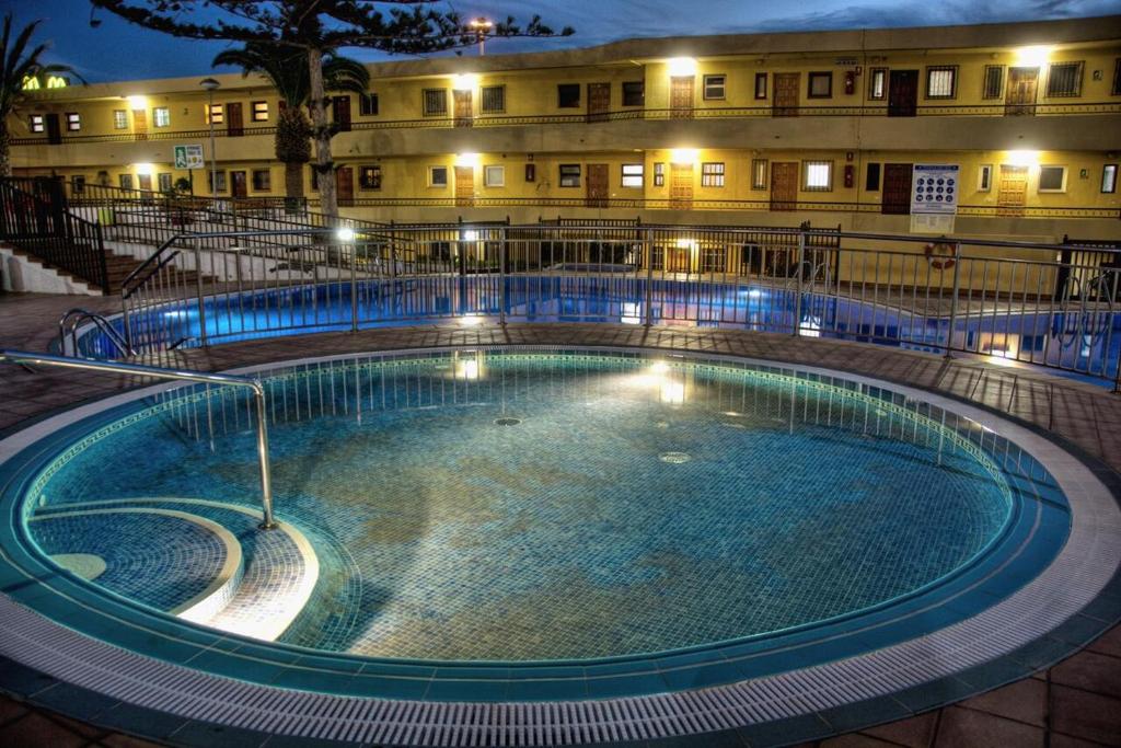 a swimming pool in front of a building at night at PLAYA LAS VISTAS LOFT in Los Cristianos