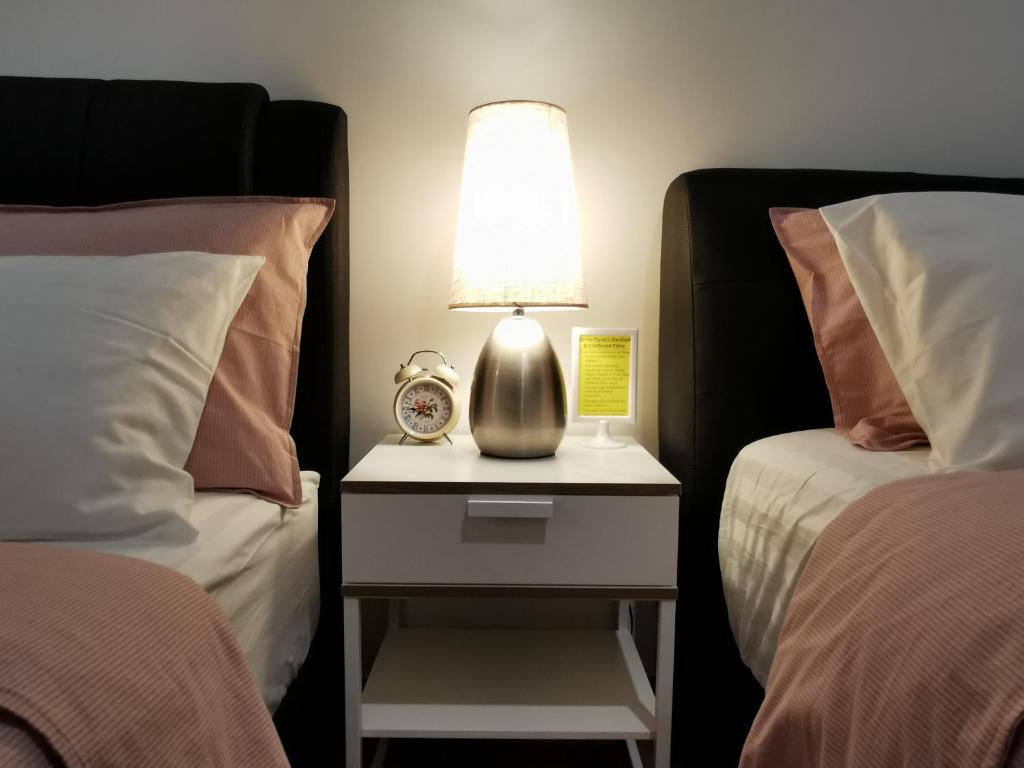a lamp on a night stand between two beds at Landmark Lovely Coast View King Suite#500mbpsWifi#Netflix in Tanjong Tokong