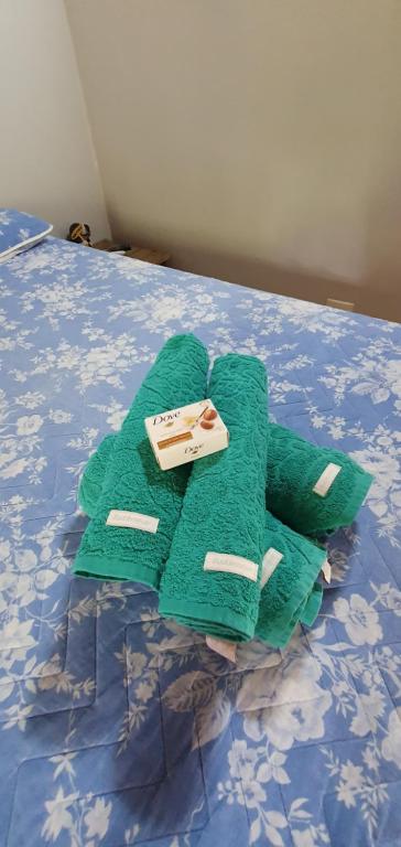 una pila de toallas verdes sentadas en una cama en Suítes no paraíso da Ilhabela, en Ilhabela