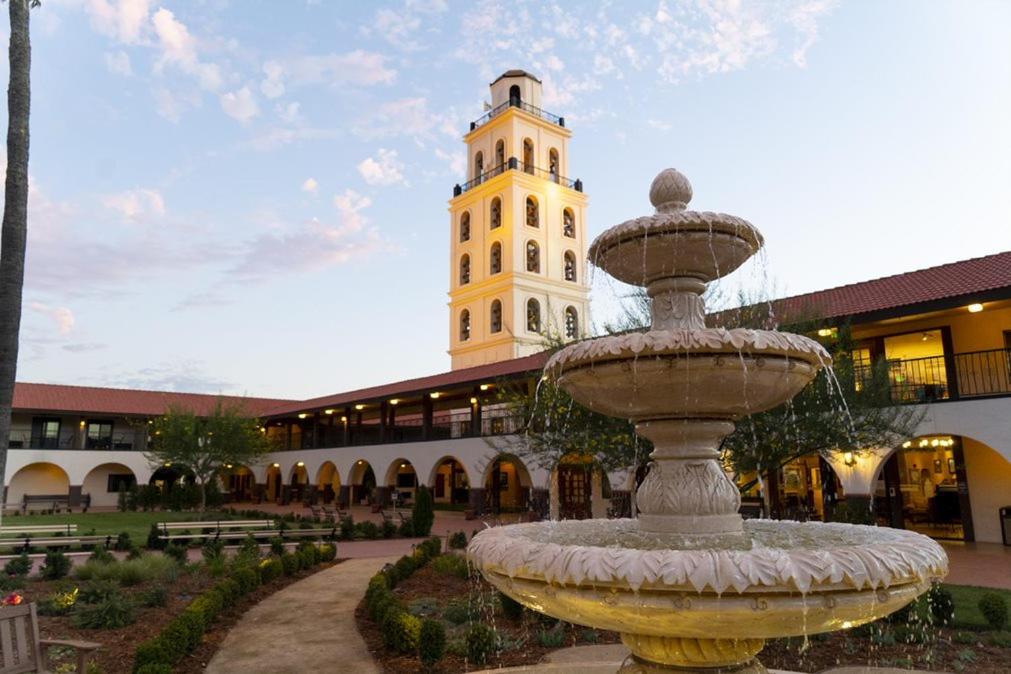 a fountain in front of a building with a clock tower at Hotel Mission De Oro in Santa Nella Village