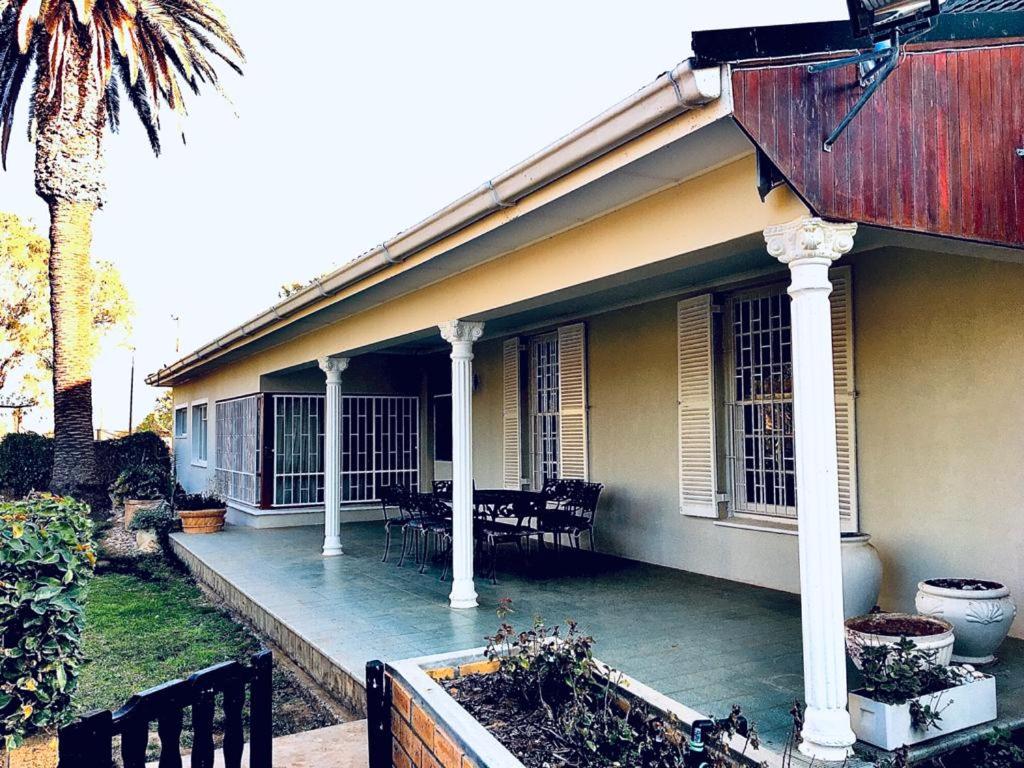 a house with a porch with chairs and a palm tree at Karoo Living in Oudtshoorn