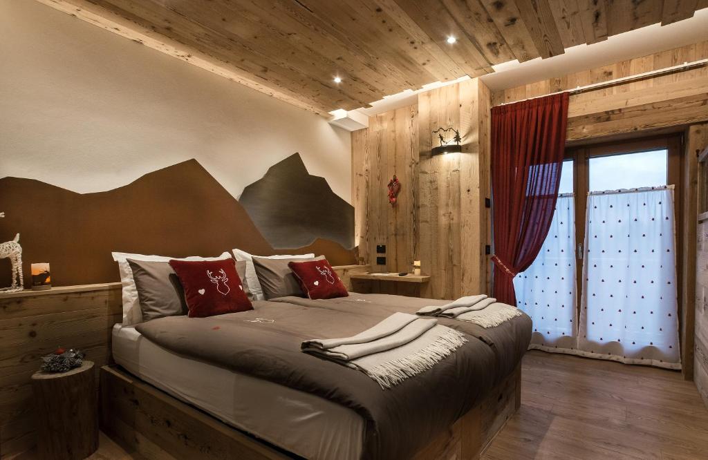 a bedroom with a large bed with red pillows at AGRITURISMO La Giasena in Ponte nellʼAlpi