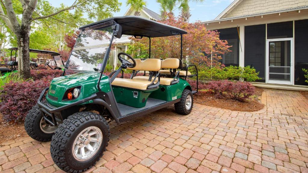 a green golf cart parked in front of a house at Bungalos 2441 in Destin