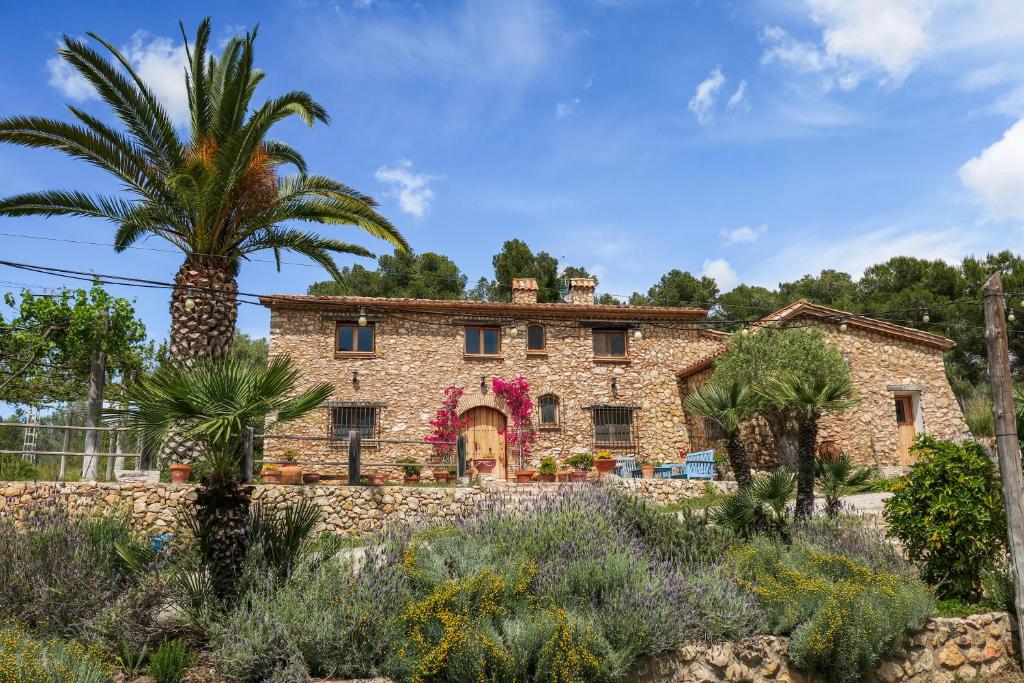 una casa in pietra con una palma di fronte di Masia Pou de la Vinya a Sitges