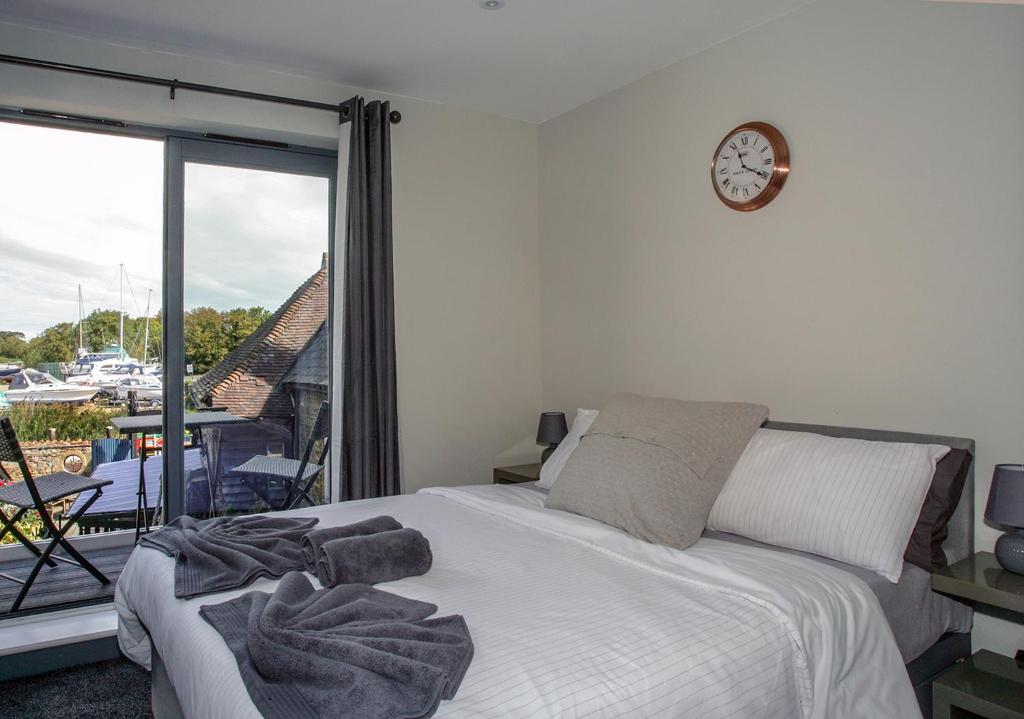 a bedroom with a bed and a clock on the wall at Beautiful river balcony cottage in heart of historic sandwich in Kent