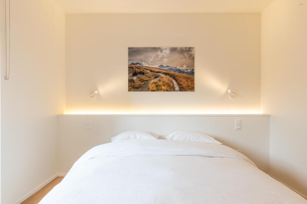 a bedroom with a white bed with a painting above it at Spacious modern appartments in the heart of Brussels in Brussels