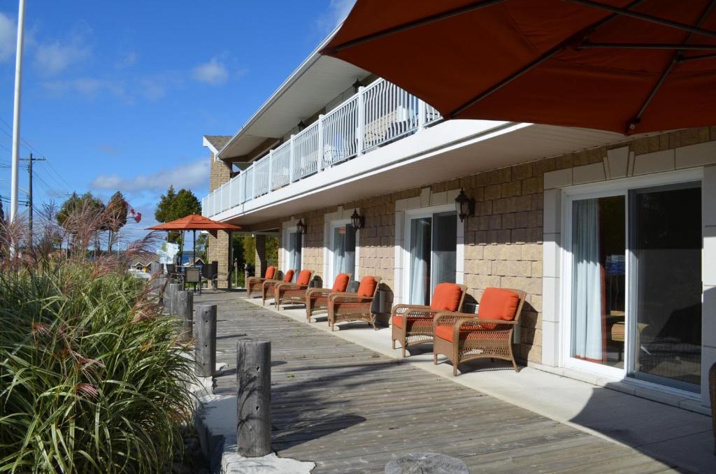 uma fila de cadeiras sentadas num alpendre com um guarda-sol em Bruce Anchor Motel and Cruises em Tobermory